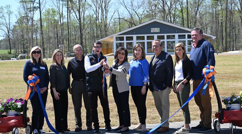 Doug Hertz (center left), founder and board chair, and Elizabeth Correll Richards (center right) hold up a pair of scissors after cutting the ribbon during the grand opening ceremony on the new campus at Camp Twin Lakes, Thursday, March 30, 2023, in Rutledge. For 30 years, Georgia children with serious illnesses, disabilities and other challenges have had access to a full camp experience at Camp Twin Lakes. On Thursday, the camp celebrated a $25 million expansion that will allow 3,500 more campers to attend each year, including some whom the camp was previously unable to serve. (Hyosub Shin / Hyosub.Shin@ajc.com)