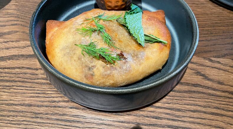The lamb hand pie at Ela has a seriously meaty filling in richly seasoned gravy and melted cheese. (Angela Hansberger for The Atlanta Journal-Constitution)