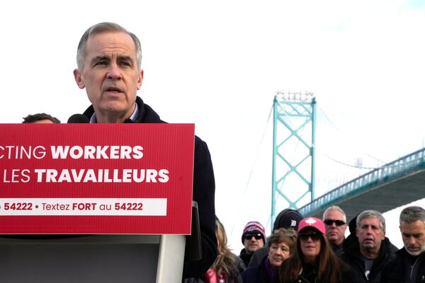 Unifor auto workers stand behind Liberal Leader Mark Carney as he speaks during a campaign stop at the Ambassador Bridge in Windsor, Ont., on Wednesday, March 26, 2025. (Frank Gunn /The Canadian Press via AP)
