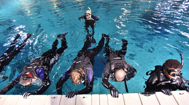 Divemaster James Beack (background) supervises a group of veterans as they prepare for a half-hour float in the 6.3 million-gallon Ocean Voyager pool at the Georgia Aquarium. HYOSUB SHIN / HSHIN@AJC.COM