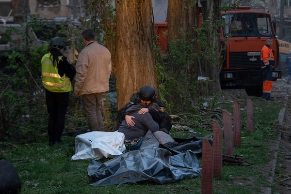 A rescue psychotherapist hugs a woman who lost a loved one, in front of the bodies of victims after a Russian strike in a residential neighborhood in Kyiv, Ukraine, Thursday, April 24, 2025. (AP Photo/Alex Babenko)
