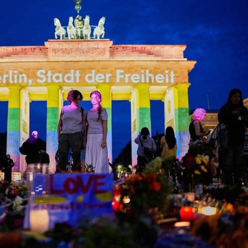 People gather in front of the Brandenburg Gate illuminated with the message "Berlin, city of freedom", commemorating the victims, after a car rammed into a crowd at the Pride March in Berlin, Sunday, July 26, 2026. (AP Photo/Ebrahim Noroozi)