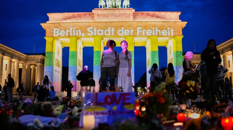 People gather in front of the Brandenburg Gate illuminated with the message "Berlin, city of freedom", commemorating the victims, after a car rammed into a crowd at the Pride March in Berlin, Sunday, July 26, 2026. (AP Photo/Ebrahim Noroozi)