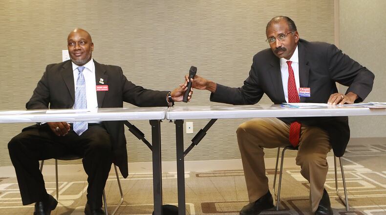 Candidates for the DeKalb County Commission Greg Adams, left, and Randal Mangham share a microphone while answering questions on how best to move the county forward during a debate at the Tucker-Reid H. Cofer Library on Nov. 29. Curtis Compton/ccompton@ajc.com