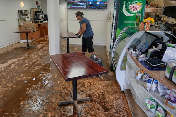 Lorena Hernandez, owner of Eddy's Kitchen, moves furniture out of her flood-damaged restaurant in North Plainfield, N.J., Tuesday, July 15, 2025. (AP Photo/Seth Wenig)