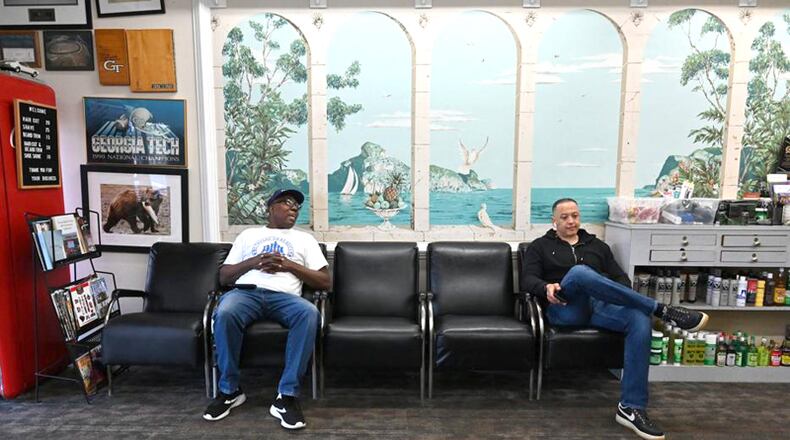 Sulaiman Smith (left) and Gustavo Espinal practice social distancing at Tommy’s Barbershop in Atlanta. Canton has ordered residents to “shelter in place” at home, and to practice social distancing if they must venture out. AJC FILE / Hyosub Shin / Hyosub.Shin@ajc.com