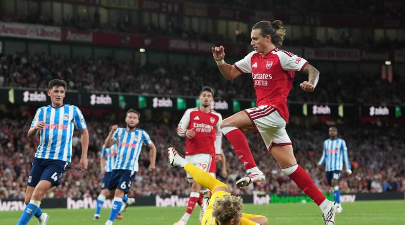 Arsenal's Riccardo Calafiori leaps over Coventry City's goalkeeper Carl Rushworth during the English Premier League soccer match between Arsenal and Coventry City in London, Friday, Aug. 21, 2026. (AP Photo/Kirsty Wigglesworth)