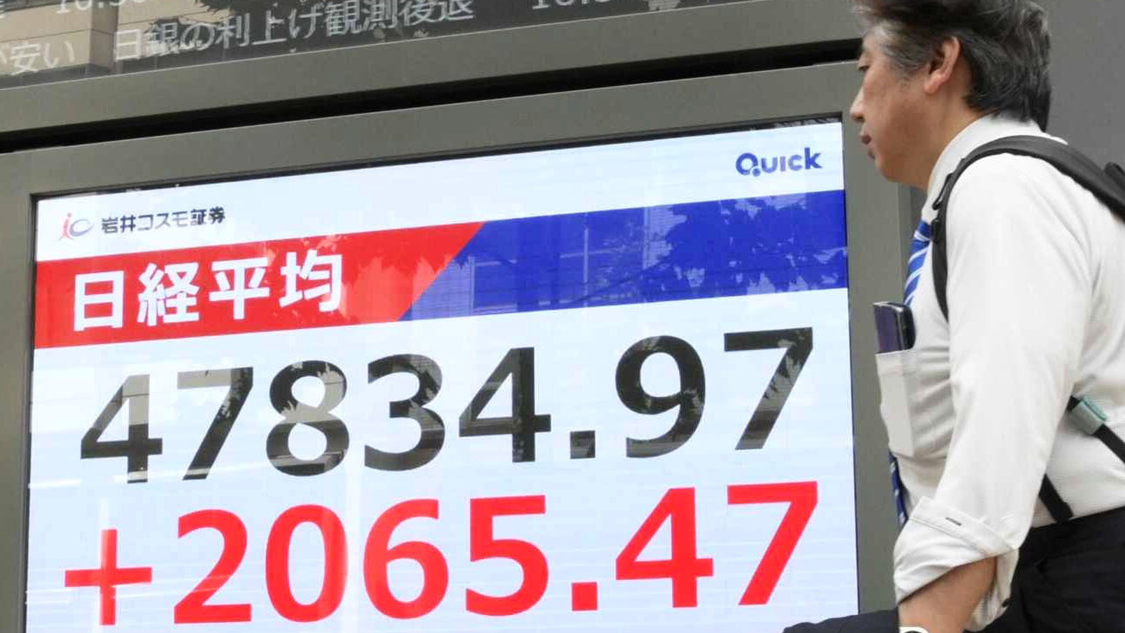 People walks by an electronic stock board showing Japan's Nikkei 225 index at a securities firm in Tokyo, Monday, Oct. 6, 2025. (Kyodo News via AP)
