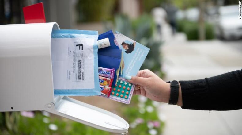 Image shows a mailbox with a white hand reaching in to grab several pieces of mail, including a package of birth control pills.