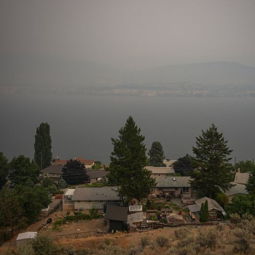 Houses are seen overlooking Okanagan Lake as smoke from the Bald Range wildfire blankets the area, in Penticton, British Columbia, Sunday, Aug. 9, 2026. (Darryl Dyck/The Canadian Press via AP)