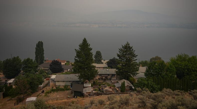 Houses are seen overlooking Okanagan Lake as smoke from the Bald Range wildfire blankets the area, in Penticton, British Columbia, Sunday, Aug. 9, 2026. (Darryl Dyck/The Canadian Press via AP)