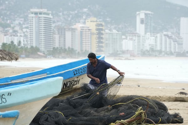 A fisherman maintains his net while his boat is off the water on Manzanillo beach as Hurricane Erick passes near Acapulco, Mexico, Thursday, June 19, 2025. (AP Photo/Fernando Llano)