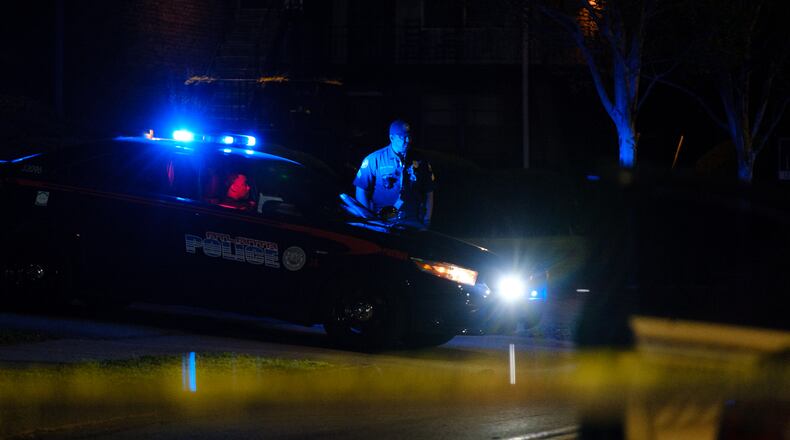 Police are seen at a scene where a man was found shot and dead inside a sedan after it crashed into a fence at a southwest Atlanta apartment complex on Friday, April 15, 2022. The crash occurred outside of the Donnelly Courts apartments. (Arvin Temkar / arvin.temkar@ajc.com)