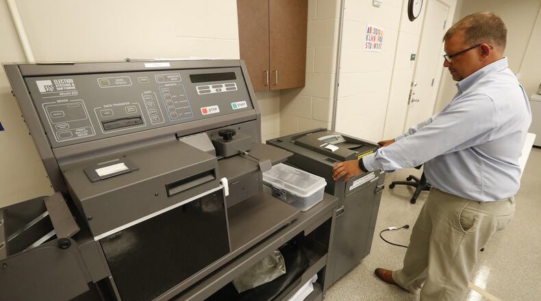 Jason Baker, the director of the Clark County Board of Elections, pulls out one of the portable voting machines that are placed in election polls and puts it next to the high-speed voting machine that’s used to count absentee ballots at the Board of Elections office on Aug. 31, 2017. Both machines are about 15 years old and require regular maintenance. Bill Lackey/Staff