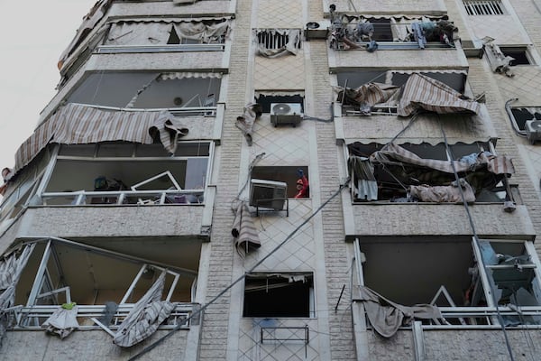 A rescue worker, centre, inspects a damaged building after an Israeli airstrike in Dahiyeh, the southern suburb of Beirut, Lebanon, Sunday, April 27, 2025. (AP Photo/Hussein Malla)
