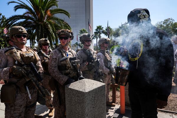 Erik, who only gave his first name, burns incense as he confronts U.S. Marines guarding the Wilshire Federal Building in Los Angeles Sunday, June 22, 2025, while anti-war demonstrators protest U.S. airstrikes on Iran's nuclear facilities. (AP Photo/Jae C. Hong)