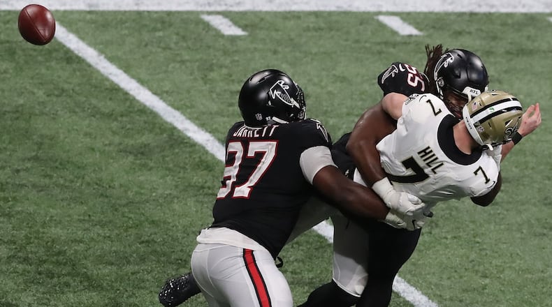 120620 ATLANTA: Atlanta Falcons Grady Jarrett (left) and Steven Means hit New Orleans Saints quarterback Taysom Hill forcing a fumble the Falcons recovered during the fourth quarter Sunday, Dec. 6, 2020, at Mercedes-Benz Stadium in Atlanta. (Curtis Compton / Curtis.Compton@ajc.com)