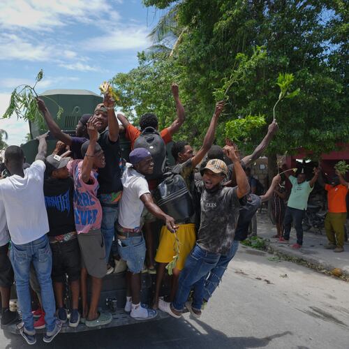 Residents of Cité Soleil celebrate the arrival of armored police vehicles during a protest to demand that police officers go and fight the gangs that control their neighborhood, in Port-au-Prince, Haiti, Tuesday, May 12, 2026. (AP Photo/Odelyn Joseph)