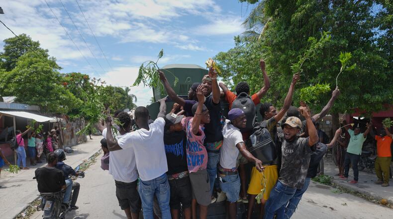 Residents of Cité Soleil celebrate the arrival of armored police vehicles during a protest to demand that police officers go and fight the gangs that control their neighborhood, in Port-au-Prince, Haiti, Tuesday, May 12, 2026. (AP Photo/Odelyn Joseph)