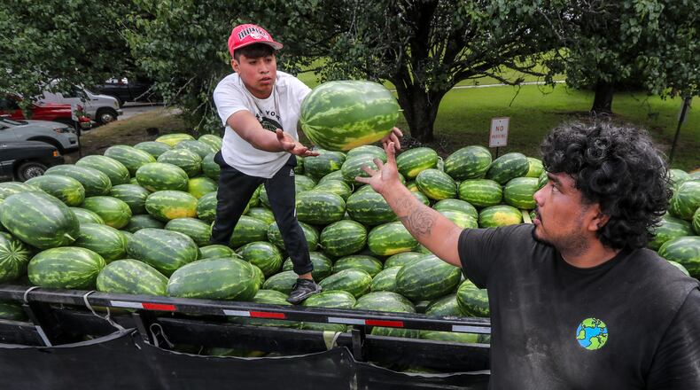 PM Produce workers, Juan Lopez (left) passes off another watermelon to Daniel Valle (right) as they load up another customer at the Atlanta State Farmers Market in Clayton County located at 16 Forest Pkwy in Forest Park.