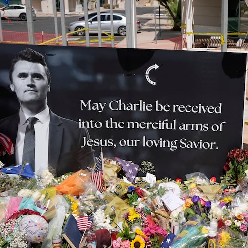 FILE - A well-wisher places flowers at a makeshift memorial set up for Charlie Kirk at Turning Point USA headquarters, Sept. 11, 2025, in Phoenix. (AP Photo/Ross D. Franklin, File)