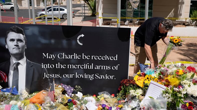 FILE - A well-wisher places flowers at a makeshift memorial set up for Charlie Kirk at Turning Point USA headquarters, Sept. 11, 2025, in Phoenix. (AP Photo/Ross D. Franklin, File)