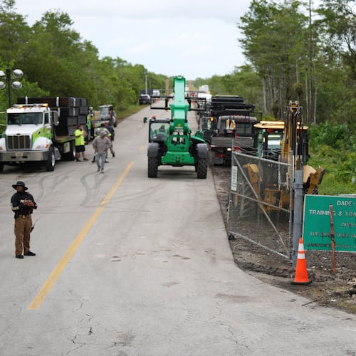 FILE - Workers install a sign reading "Alligator Alcatraz" at the entrance to the migrant detention facility at Dade-Collier Training and Transition facility, July 3, 2025, in Ochopee, Fla. (AP Photo/Rebecca Blackwell, file)