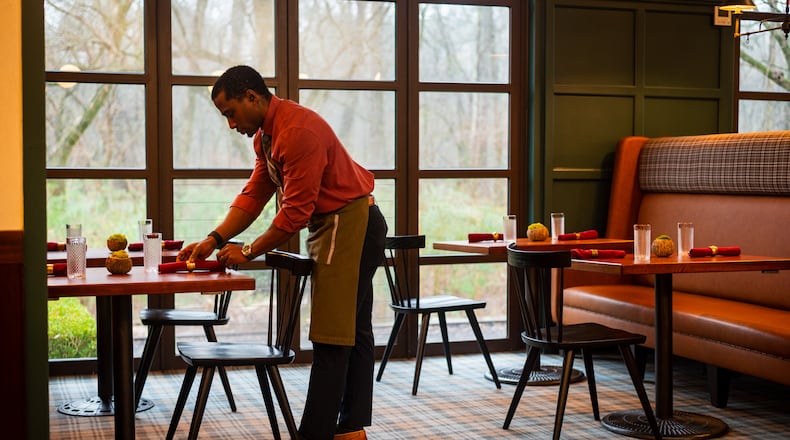 Rell Hall sets up the dining room at Nadair, Kevin Gillespie's Scottish fine dining restaurant. Gillespie admits “no one asked for” this food combination of Southern and European cuisines, but his strikingly clear vision gives the restaurant an immediate appeal. (Henri Hollis/AJC)