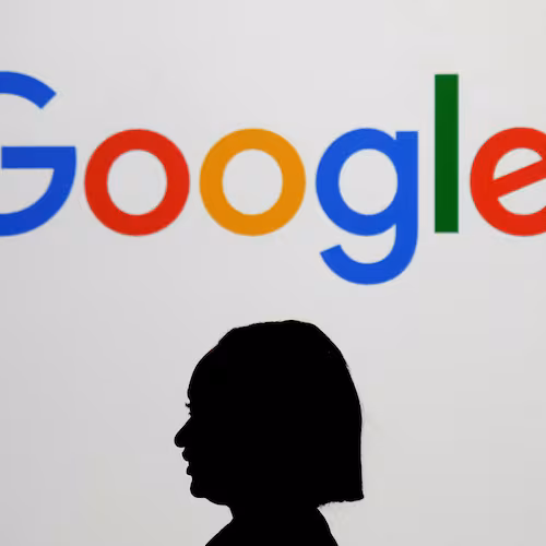 FILE - A woman walks by a giant screen displaying the Google logo at an event at the Paris Google Lab on the sidelines of the AI Action Summit in Paris, Feb. 9, 2025. (AP Photo/Thibault Camus, File)