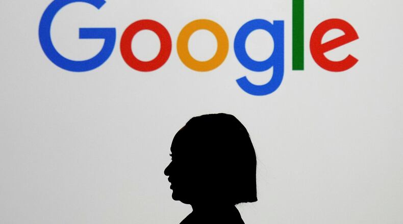 FILE - A woman walks by a giant screen displaying the Google logo at an event at the Paris Google Lab on the sidelines of the AI Action Summit in Paris, Feb. 9, 2025. (AP Photo/Thibault Camus, File)