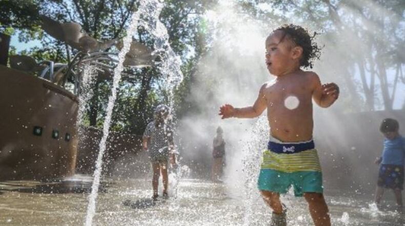 Nicolas Chapman enjoys cooling off at the splash pad at the Atlanta Botanical Garden on Friday. JOHN SPINK / JSPINK@AJC.COM