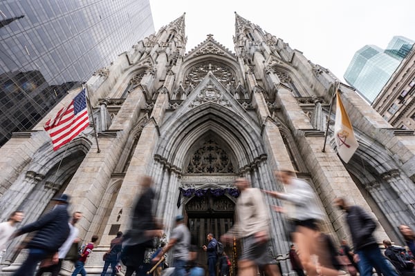 People walk past St. Patrick's Cathedral as dark drapes hang over the doorway before a memorial mass for the late Pope Francis, Saturday, April 26, 2025, in New York. (AP Photo/Julia Demaree Nikhinson)