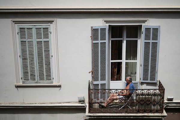 A man sits on the balcony during a electricity outage in Cannes, southern France, Saturday, May 24, 2025. (AP Photo/Natacha Pisarenko)