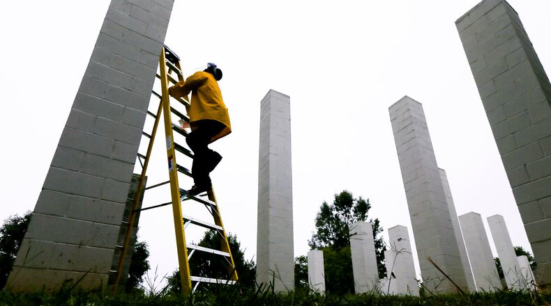 September 6, 2012 Atlanta: Kenneth Simpson of Starbrite window cleaning climbed one of the 54 columns at the corner of Glen Iris Drive and Highland Avenue in Atlanta on Thursday, Sept. 6, 2012 where he and a colleague (not pictured) were stripping the paint away from the art project. The project, that is entitled "54 Columns" was erected in 1999 by artist, Sol LeWitt - has 54 columns ranging from 10 to 20 feet high in a 112 foot X 176 foot triangular layout that integrates art and architecture making a geometric reference to the forms reflecting a skyline of an urban environment. Simpson has been spraying a stripping solution across the painted surfaces and then pressure washes them exposing the bare surface. It is his understanding that the columns would then be repainted at a later time as part of a conservation project underway by the Fulton County Public Art Program. The Fulton County Public Art Program was contacted about what the future plans of the project might be - but they did not return AJC phone call inquiries. JOHN SPINK / JSPINK@AJC.COM