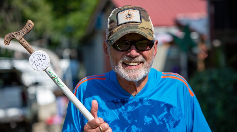 Jim Merritt, 73, of Buford, holds the white stick he took with him on his runs. He was nearing the important anniversary of 20 years of running every single day until COVID cut that streak short. He wasn't a runner when he began running 23 years ago. PHIL SKINNER FOR THE ATLANTA JOURNAL-CONSTITUTION.