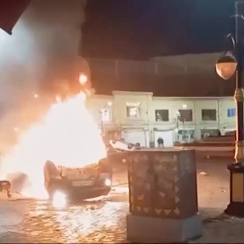 This frame grab from a video released Friday, Jan. 9, 2026, by Iranian state television shows a man holding a device to document burning vehicles during a night of mass protests in Zanjan, Iran. (Iranian state TV via AP)