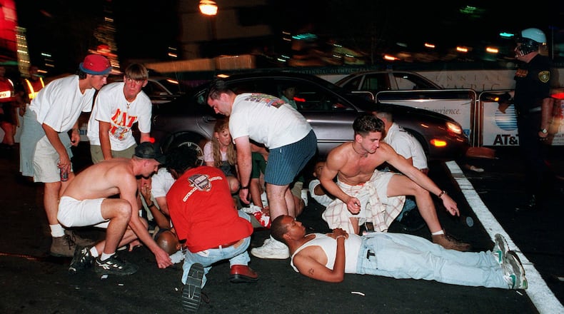 Spectators tend to injured victims following an early morning explosion in Atlanta's Olympic Centennial Park Saturday, July 27, 1996. The downtown park was crowded with Olympic visitors and revelers at the time of the explosion, which killed a woman and injured more than 100 other people.
