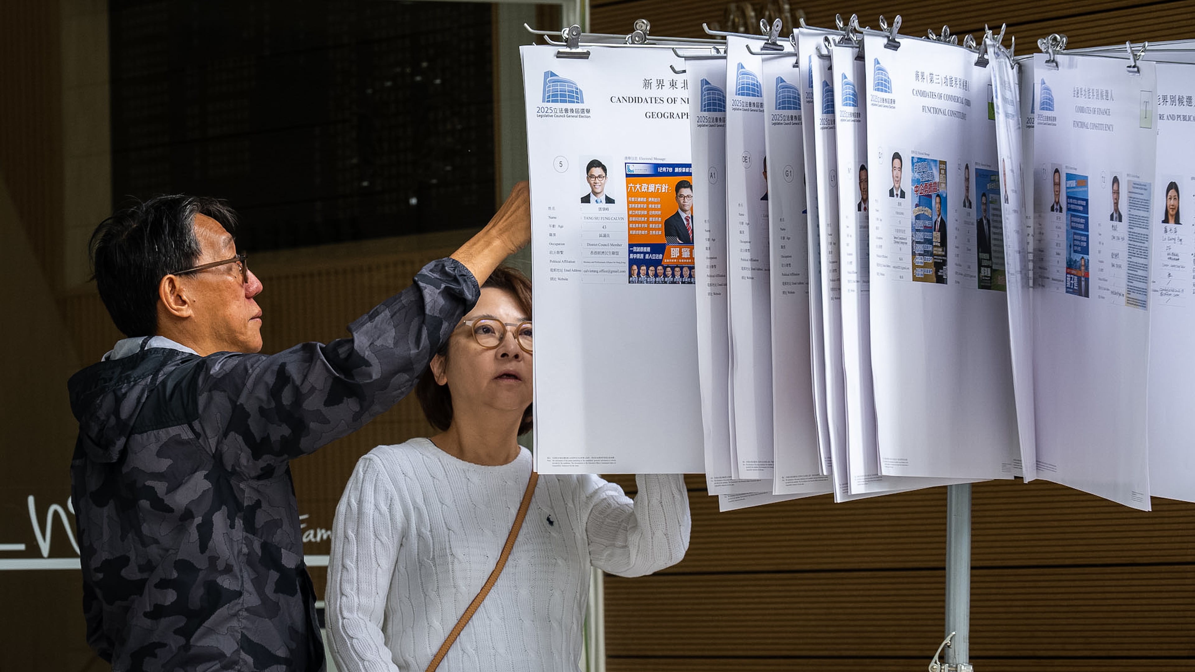 People read the candidates information at a polling station near the site of the fire at Wang Fuk Court in the Tai Po district during the Legislative Council General Election in Hong Kong on Sunday, Dec. 7, 2025. (AP Photo/Chan Long Hei)