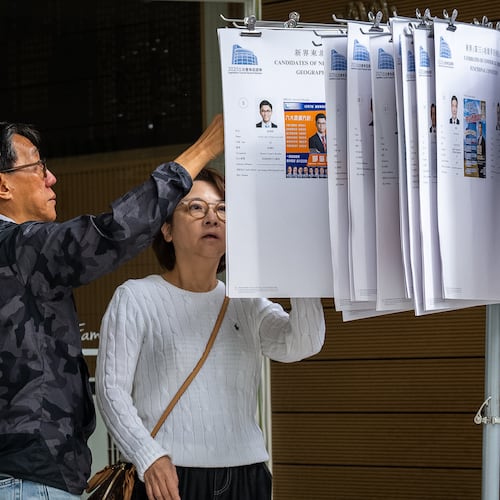 People read the candidates information at a polling station near the site of the fire at Wang Fuk Court in the Tai Po district during the Legislative Council General Election in Hong Kong on Sunday, Dec. 7, 2025. (AP Photo/Chan Long Hei)