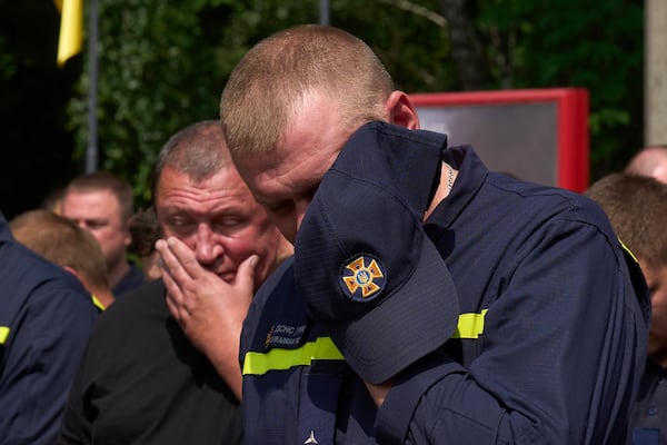 Colleagues are overcome by emotion as say the last goodbye to firefighters Pavlo Yezhor, Danylo Skadin, and Andriy Remenny, killed by Russia's missile attack last week, at the farewell ceremony in front of the fire station in Kyiv, Ukraine, Monday, June 9, 2025. (AP Photo/Efrem Lukatsky)