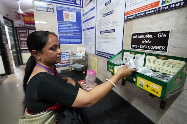 Asha worker Shashi Mishra collects oral rehydration solution pouches before leaving for her job from an urban health center in Ahmedabad, India, Wednesday, April 2, 2025. (AP Photo/Ajit Solanki)
