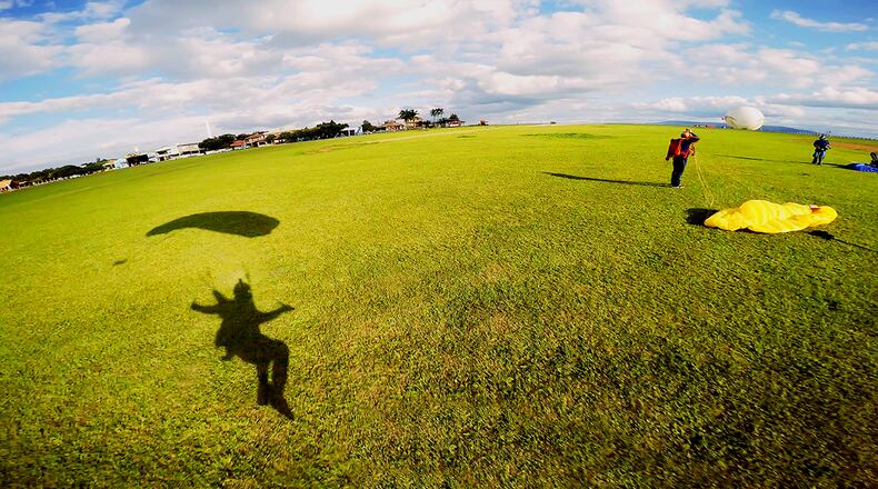 A skydiver’s shadow is seen on grass during landing