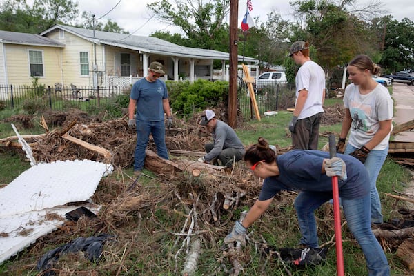 Volunteers from Kerrville Bible Church saw and haul tree debris in front of a flood-damaged home on Guadalupe Street in Kerrville, Texas, on Saturday, July 12, 2025. (AP Photo/Gabriela Aoun Angueira)
