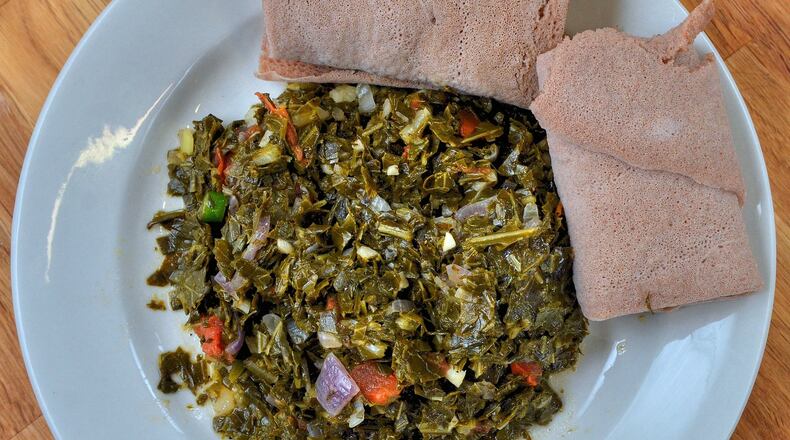 Yohana Solomon, who came to the U.S. from Ethiopia, says Gomen (Collard Greens) will seem familiar to Southern cooks. It’s shown with injera, a fermented flatbread. STYLING BY YOHANA SOLOMON / CONTRIBUTED BY CHRIS HUNT PHOTOGRAPHY
