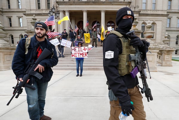 FILE - Men carry rifles near the steps of the State Capitol building in Lansing, Mich., on April 15, 2020 during a protest over Michigan Gov. Gretchen Whitmer's orders to keep people at home and businesses locked during the coronavirus outbreak. (AP Photo/Paul Sancya, File)