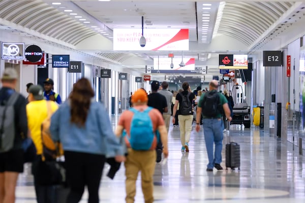 Travelers walk through Concourse E at the Hartsfiel-Jackson International Airport in 2023. (Miguel Martinez /AJC)