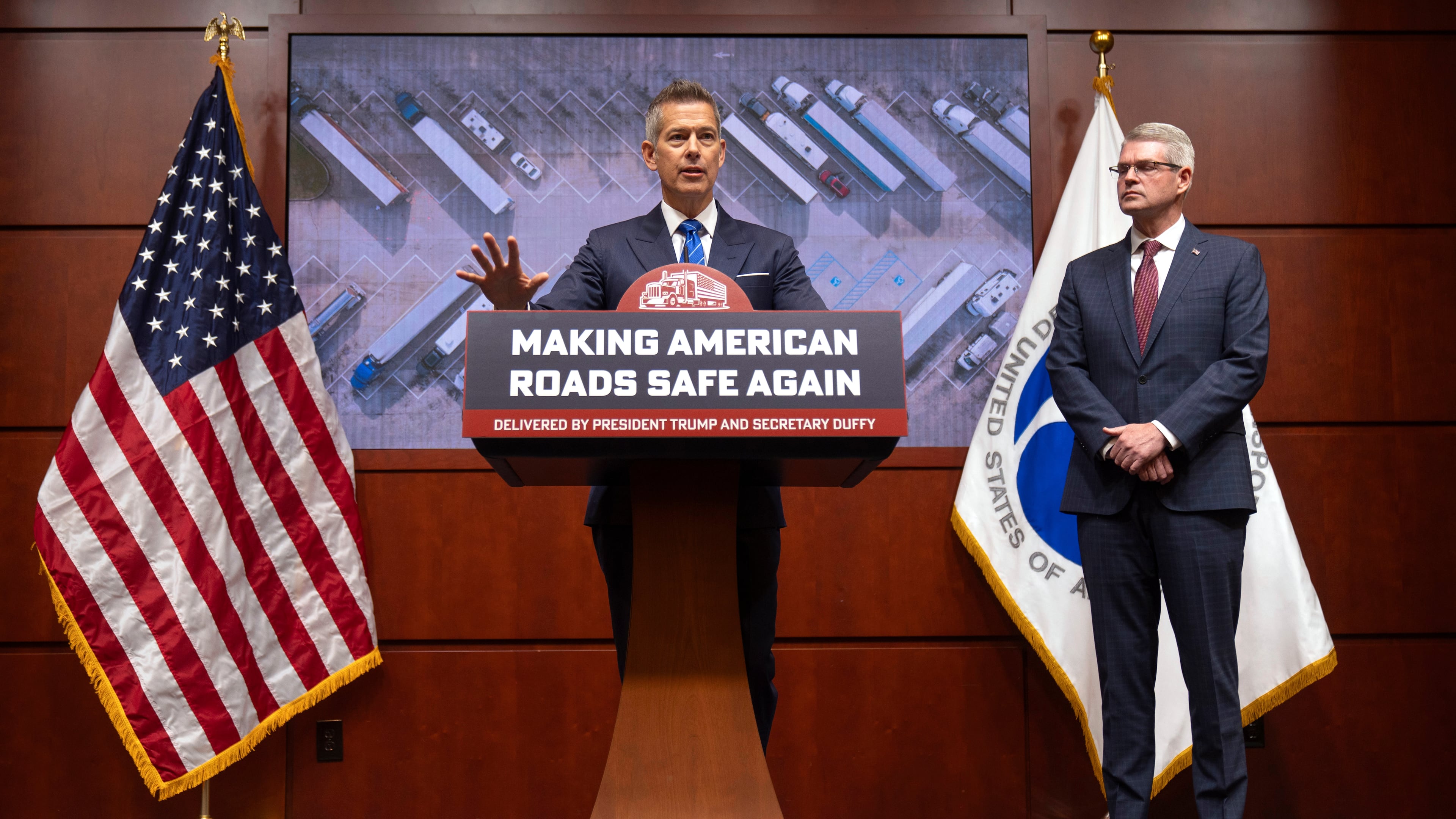 Transportation Secretary Sean Duffy speaks as Derek Barrs, Administrator of the Federal Motor Carrier Safety Administration, listens during a news conference at the Department of Transportation in Washington, Friday, Dec. 12, 2025. (AP Photo/Mark Schiefelbein)