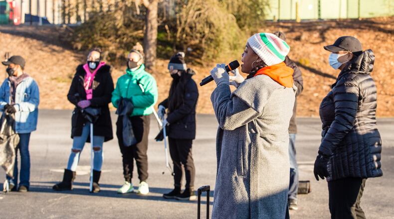 Volunteers gather and listen to instructions from Georgia STAND-UP's executive organizer Ariel Singleton, on microphone, at Impact Church before picking up trash in the in East Point community on Martin Luther King, Jr Day on Monday, January 18, 2021.   (Jenni Girtman for The Atlanta-Constitution)