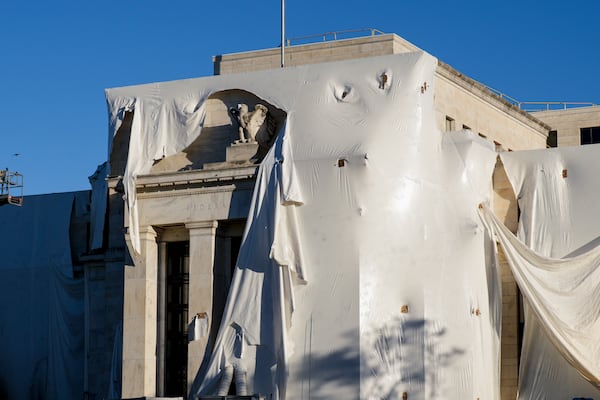 FILE - The sculpture of an eagle looks out from behind protective construction wrapping on the facade as the Federal Reserve Board Building undergoes both interior and exterior renovations, in Washington, Monday, Oct. 23, 2023. (AP Photo/J. Scott Applewhite, File)
