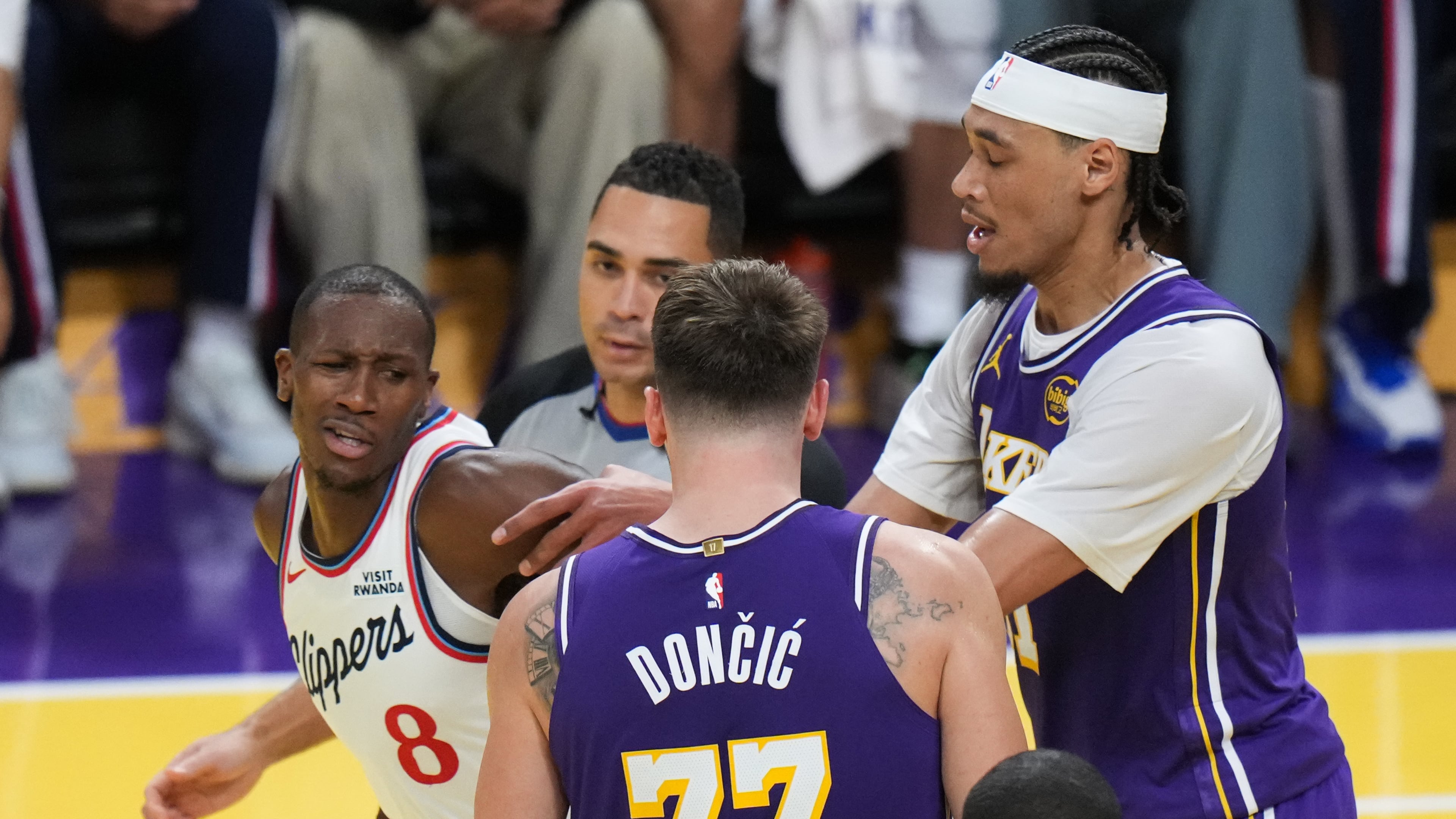Los Angeles Clippers guard Kris Dunn (8) is pushed by Los Angeles Lakers center Jaxson Hayes (11) after Dunn shoved the ball into Luka Doncic's chest during the second half of an NBA Cup basketball game Tuesday, Nov. 25, 2025, in Los Angeles. (AP Photo/Jae C. Hong)